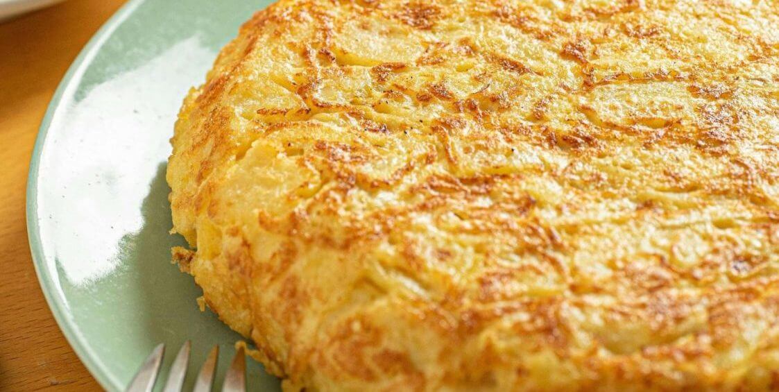 Spanische Tortilla Rezept. Tortilla im Ganzen auf einem Teller – klassisch und goldbraun gebraten.