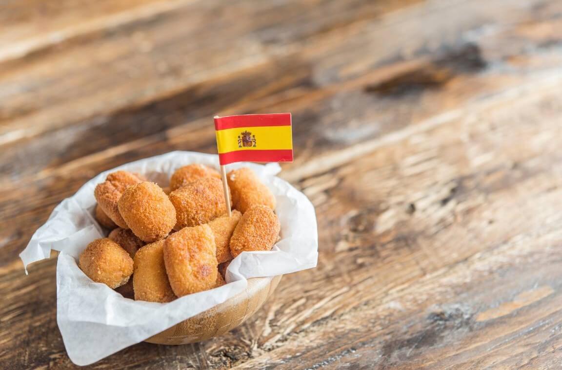 Spanische Kroketten Rezept - Ein Schälchen mit knusprigen spanischen Croquetas, dekoriert mit einer kleinen spanischen Flagge