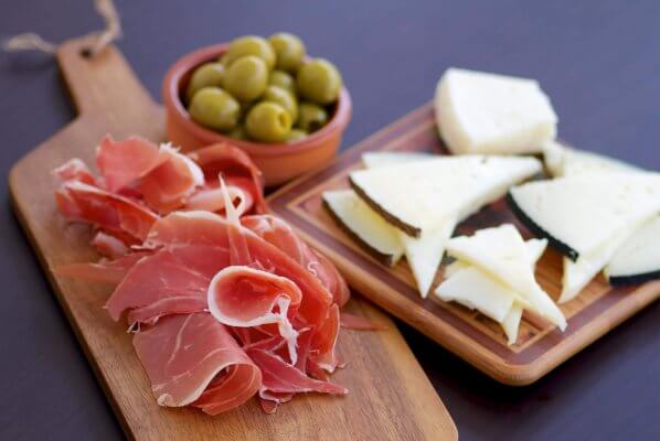 Was sind Tapas? -Platte mit spanischem Manchego-Käse, Serrano-Schinken und grünen Oliven