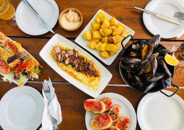 Was sind Tapas? - Vier Teller mit verschiedenen Tapas auf einem Holztisch