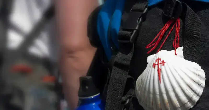 Jakobsmuschel mit Kreuz des Santiago-Ordens an einem Rucksack auf dem Jakobsweg